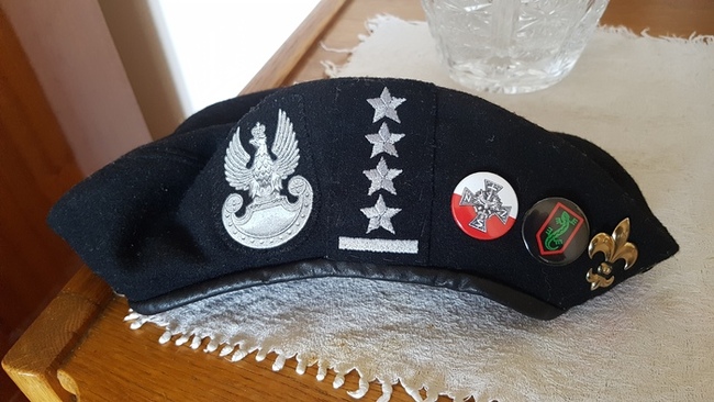 Mundurowy beret kapitana Leszka Zabłockiego z oznaczeniem jego oficerskiego stopnia, dwoma wpinkami pamiątkowymi NSZ i harcerską lilijką.